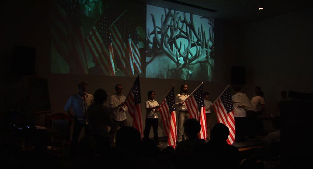 Several people on stage holding American flags