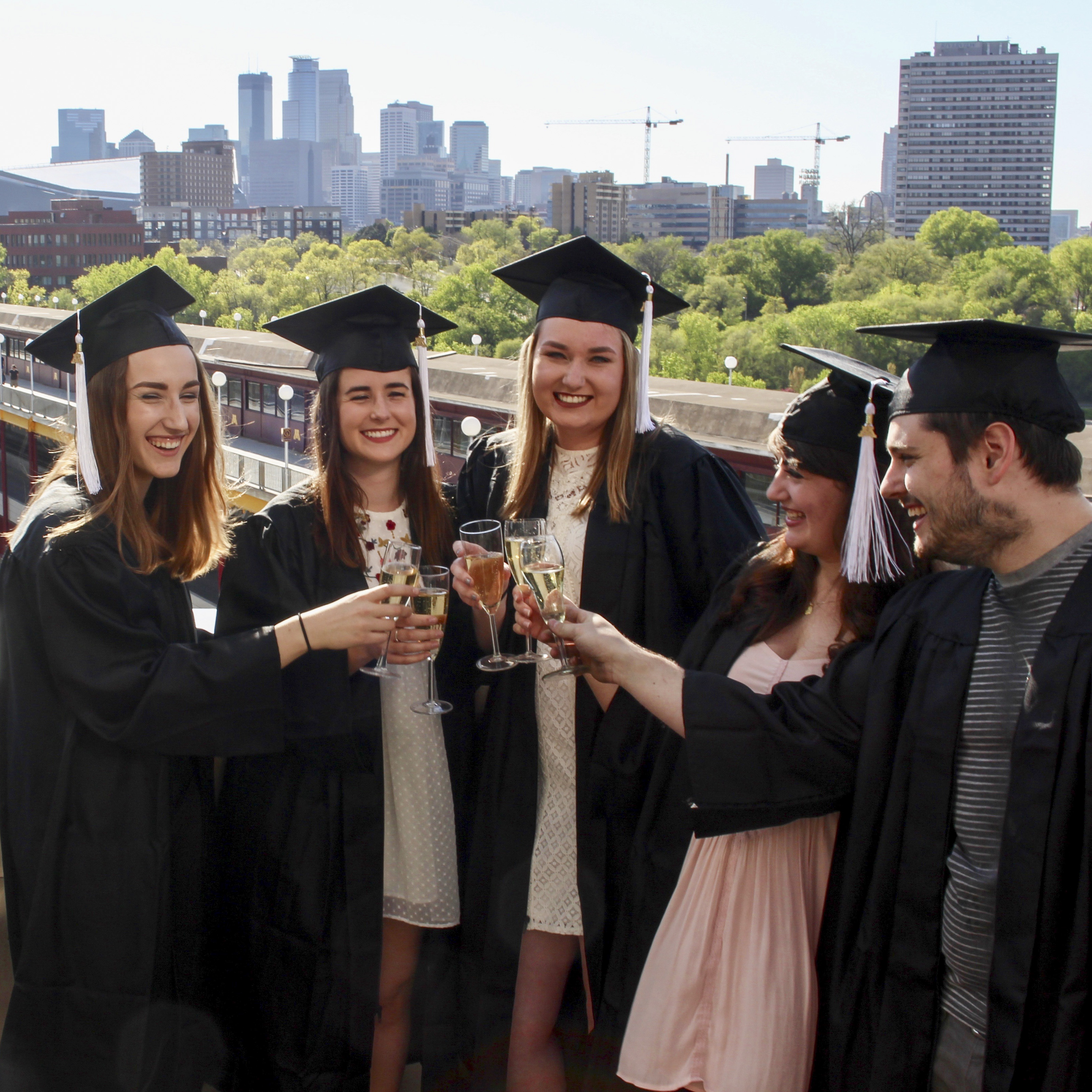 5 people in graduation uniforms toasting