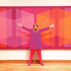 A person standing in front of a purple-ish art piece