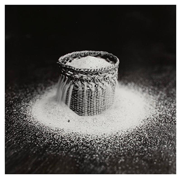 black and white photo of sand overflowing from woven basket