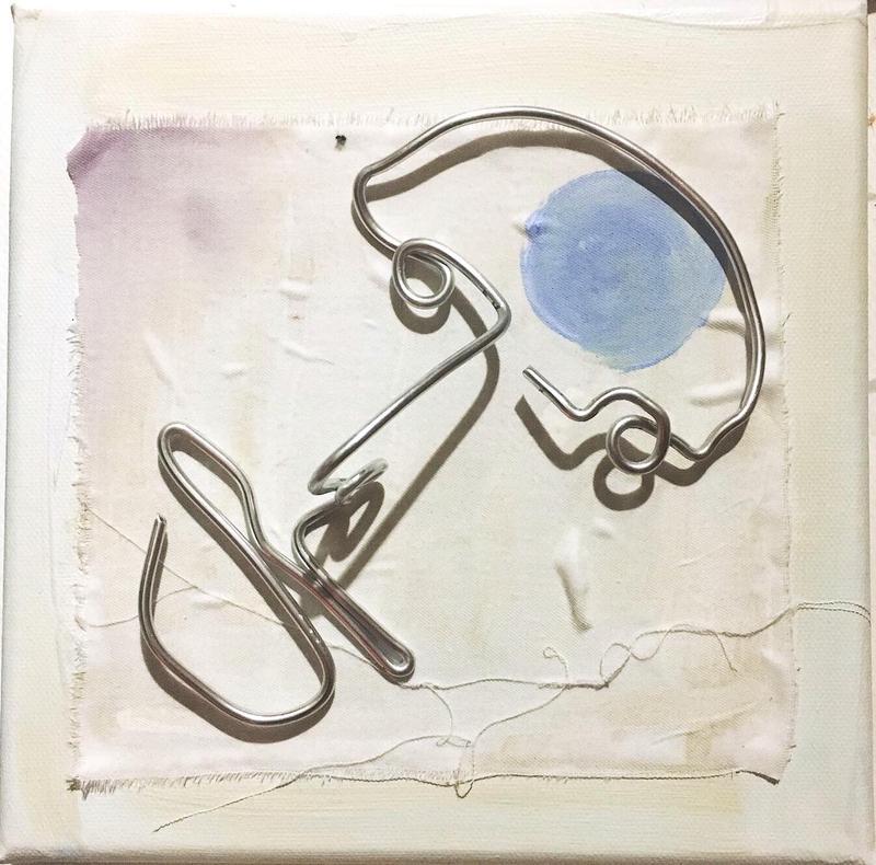 A bent wire frame, shaped to form an abstract fact sits on a torn canvas