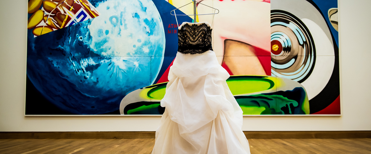 wedding dress displayed in front of large art piece