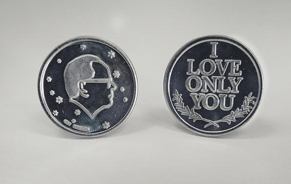 Two silver "commemorative" coins with the artist's profile surrounded by stars (on one side) and the words "I love only you" on the other side. 