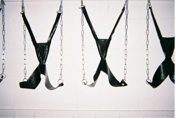 leather "x" shaped braces with metal chains are suspended from the ceiling. 
