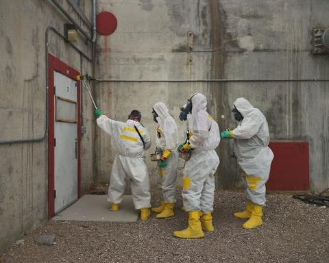4 people in painting protective clothing near a white door