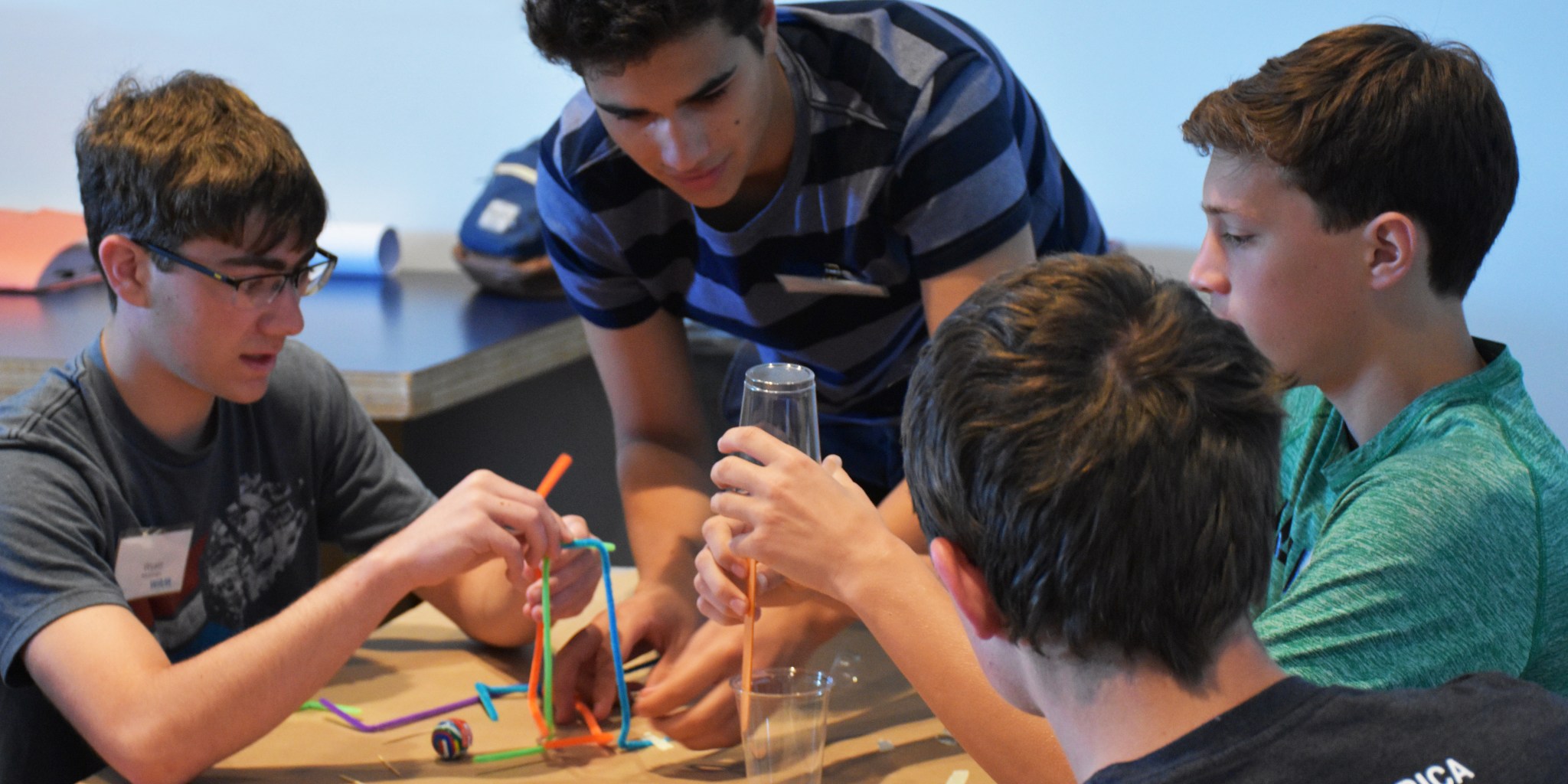mentor helping students build plastic models on a desk