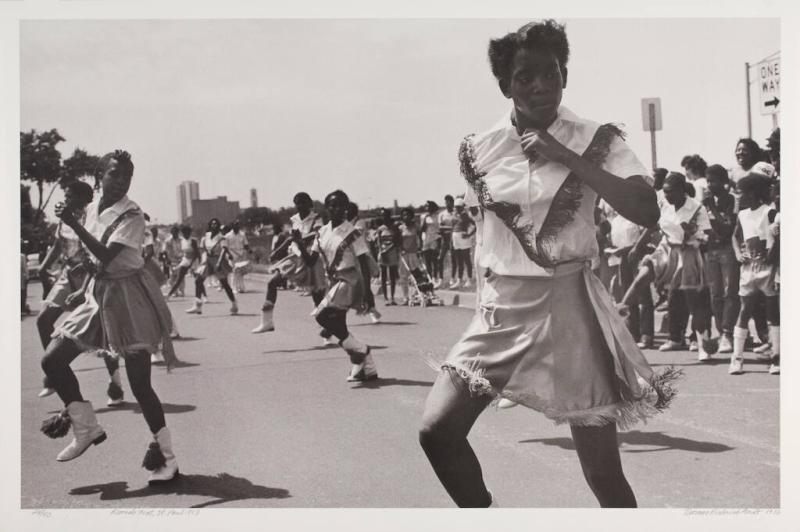 A group of school-age children march in formation for a parade in this black and white photograph.
