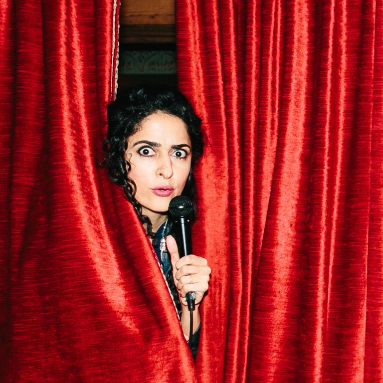Suzie with a mic behind a red curtain
