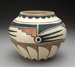 Cream colored pot with geometric black and red design covering the entire surface of the pot.