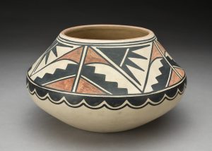 Cream colored pot with geometric black and red design covering the upper two-thirds of the pot.