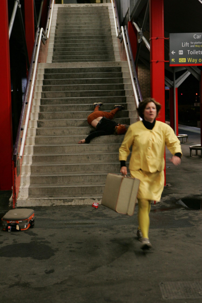 A person in yellow clothing running from stairs with a briefcase in hand