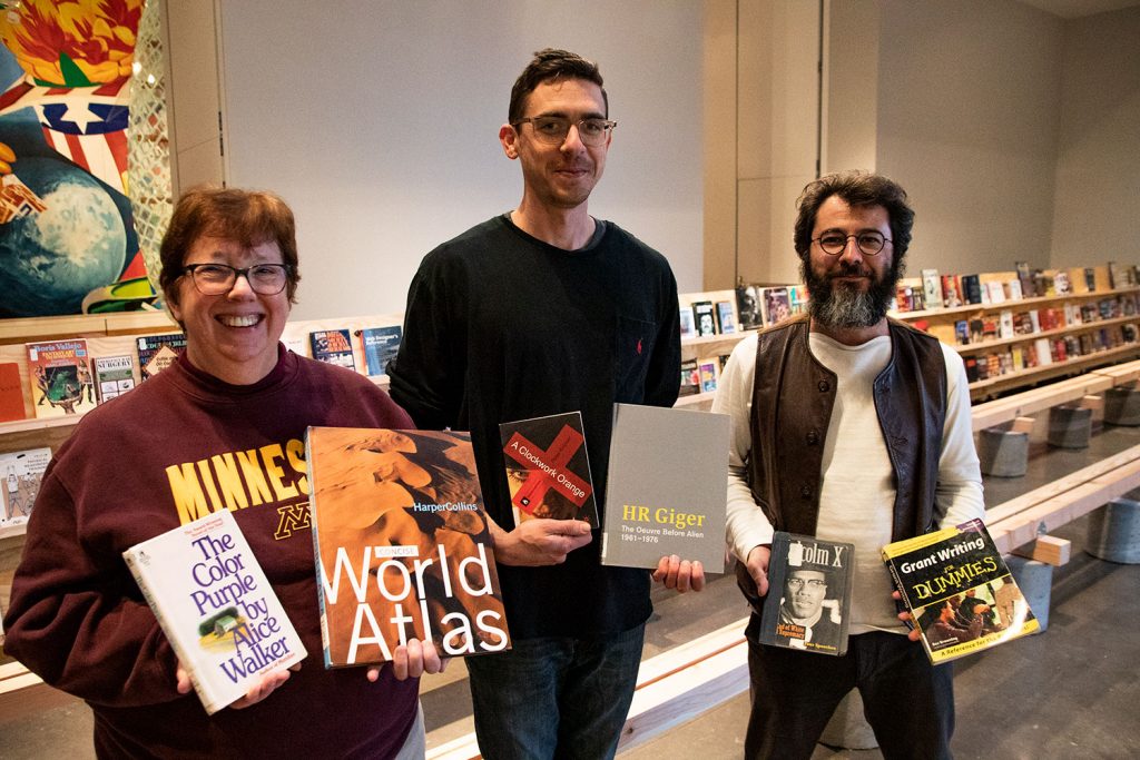 Librarian Betsy Friesen, artist Daniel McCarthy Clifford, and curator Boris Oicherman standing together in the Target Studio, holding books banned in U.S. prisons.