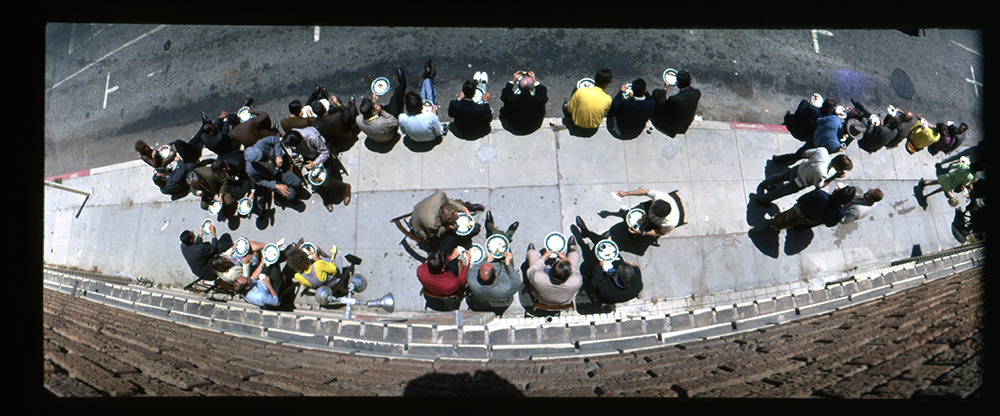 A birdseye view of people sitting on a sidewalk through a fisheye lens