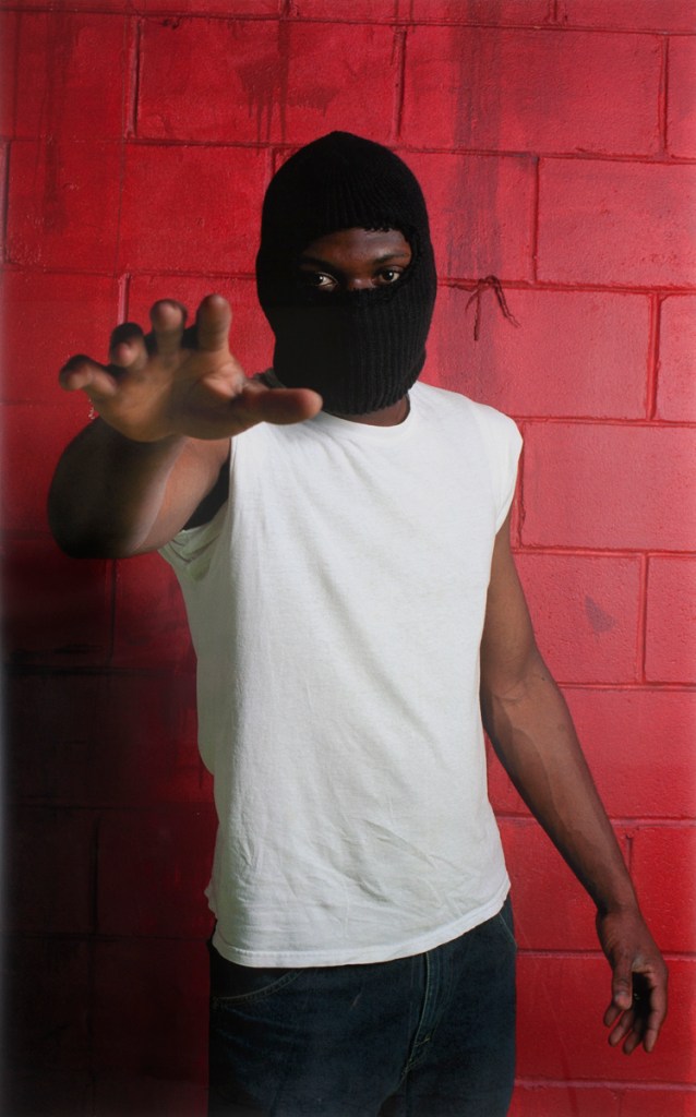 person wearing mask against red brick wall