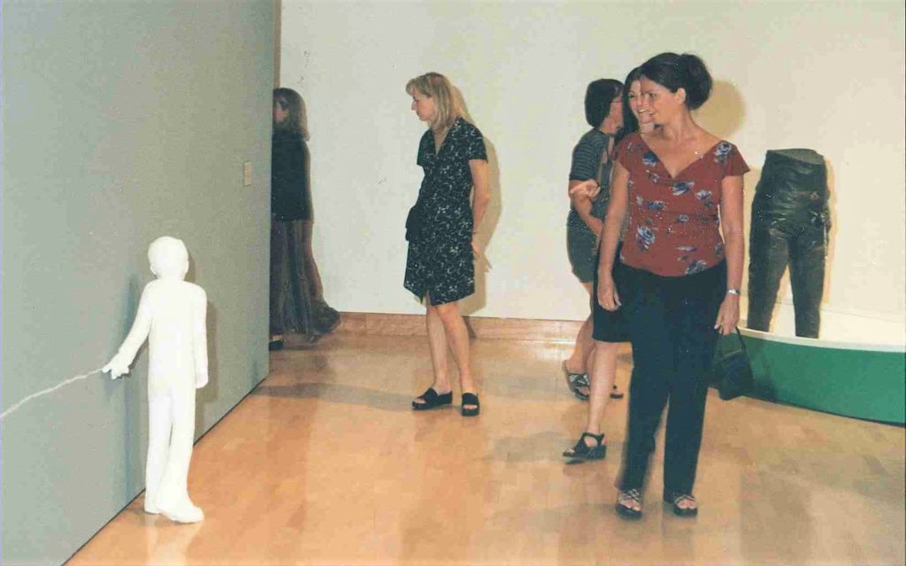A person looking at a small white statue