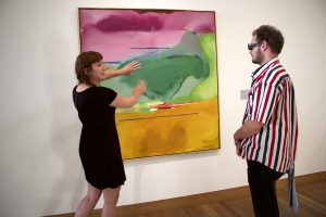 A person gesticulating to a painting