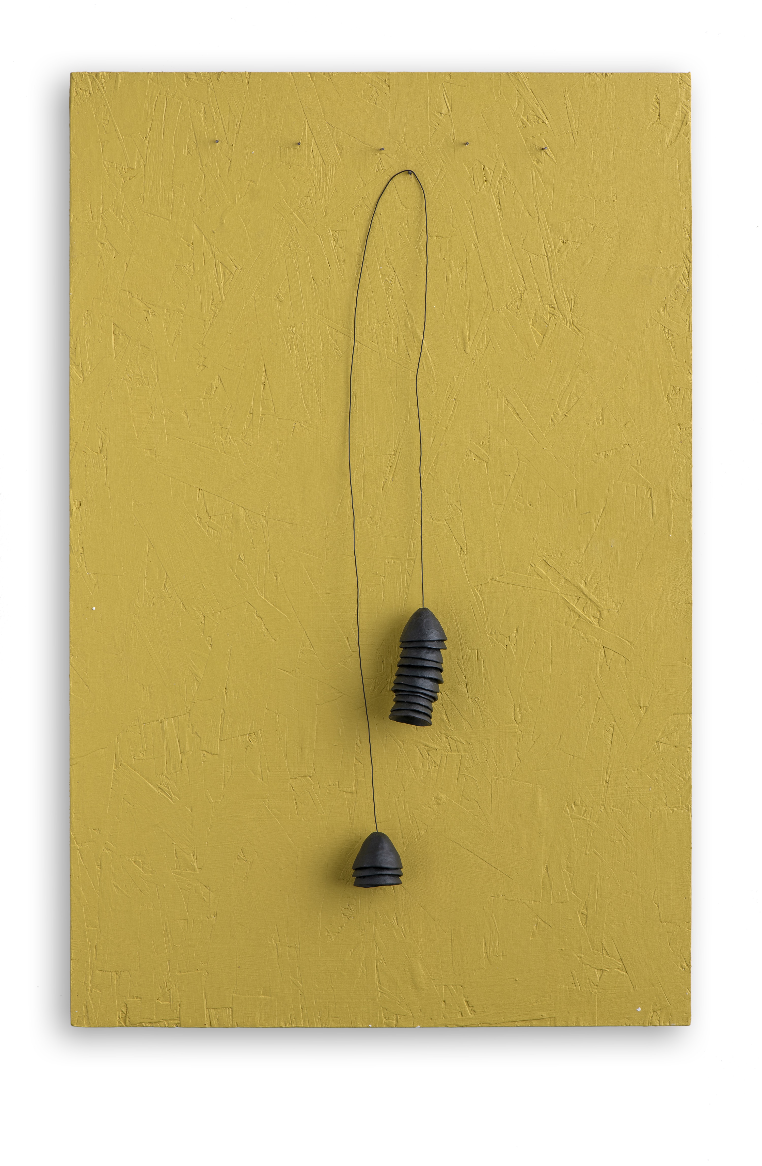 A black wire hanging on a yellow wall