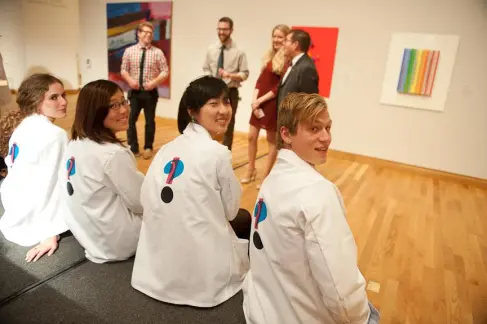 4 people in matching white coats with a question mark on the back