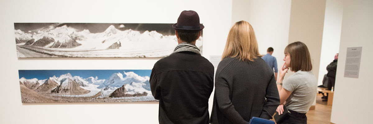 three people looking at art pieces on wall