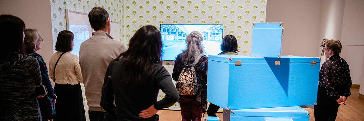 a group of people standing among artwork viewing images on a monitor