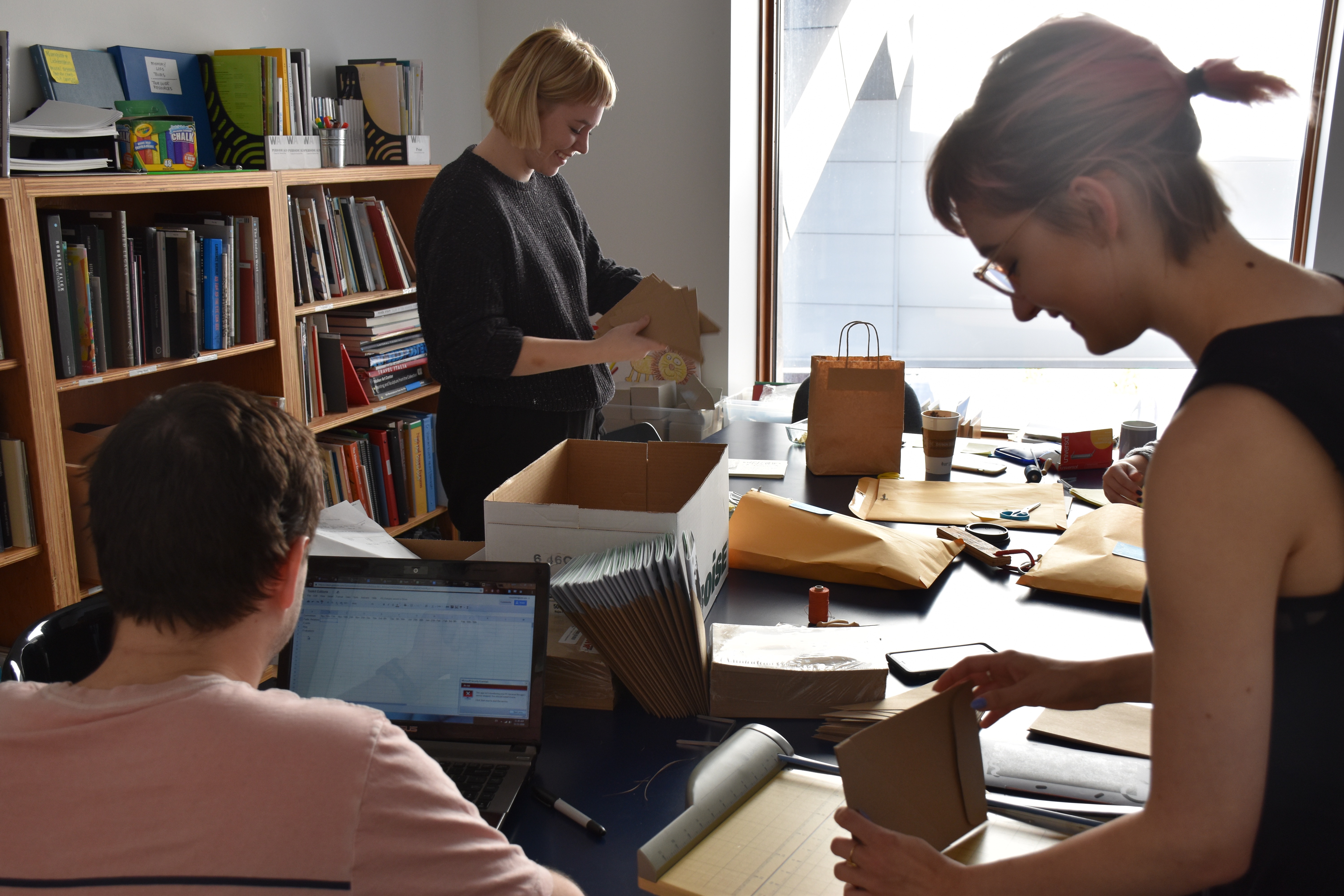 WAM Collective Members Keith Murphy, Lexi Herman, and Anya Udovik assembling our hand-bound Wellness Toolkits