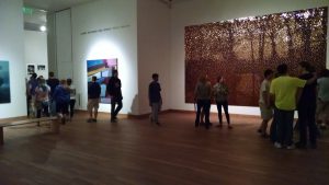 A crowd looing at a large shimmering artwork