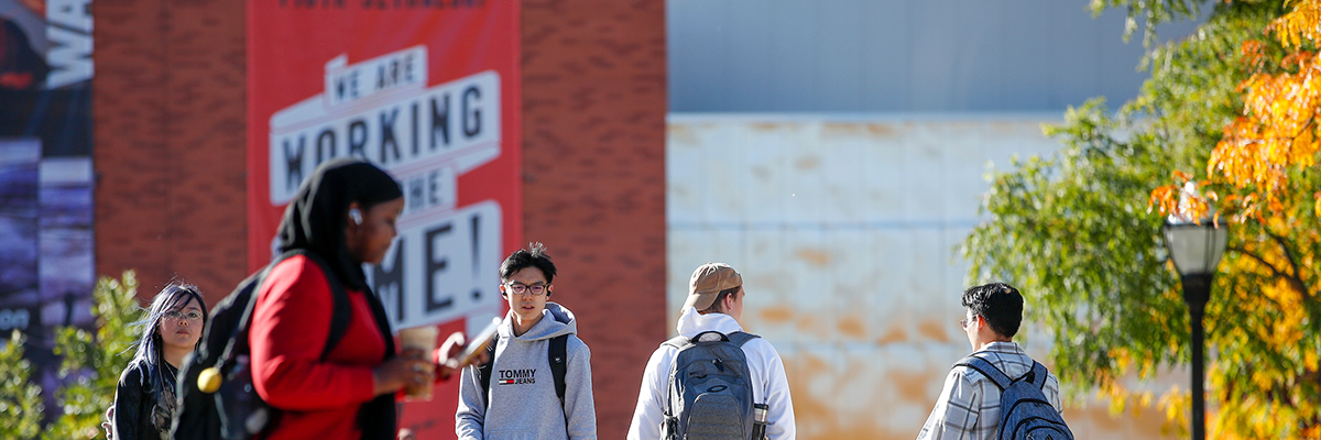 students walking in front of large red exhibition sign