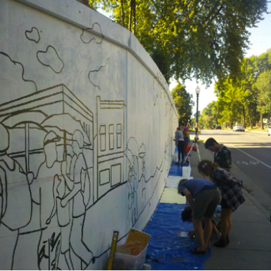 A row of people working on a mural