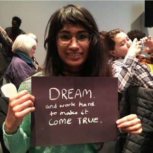 a person holding a sign saying 'dream and work hard to make it come true'