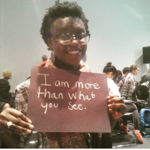 A person holding holding a sign saying 'I am more than what you see'