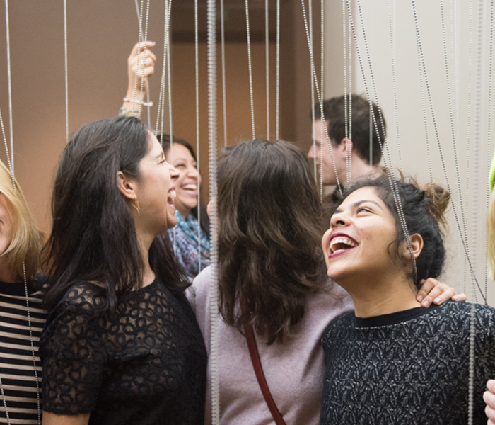 people laughing in an interactive exhibit of hanging beads