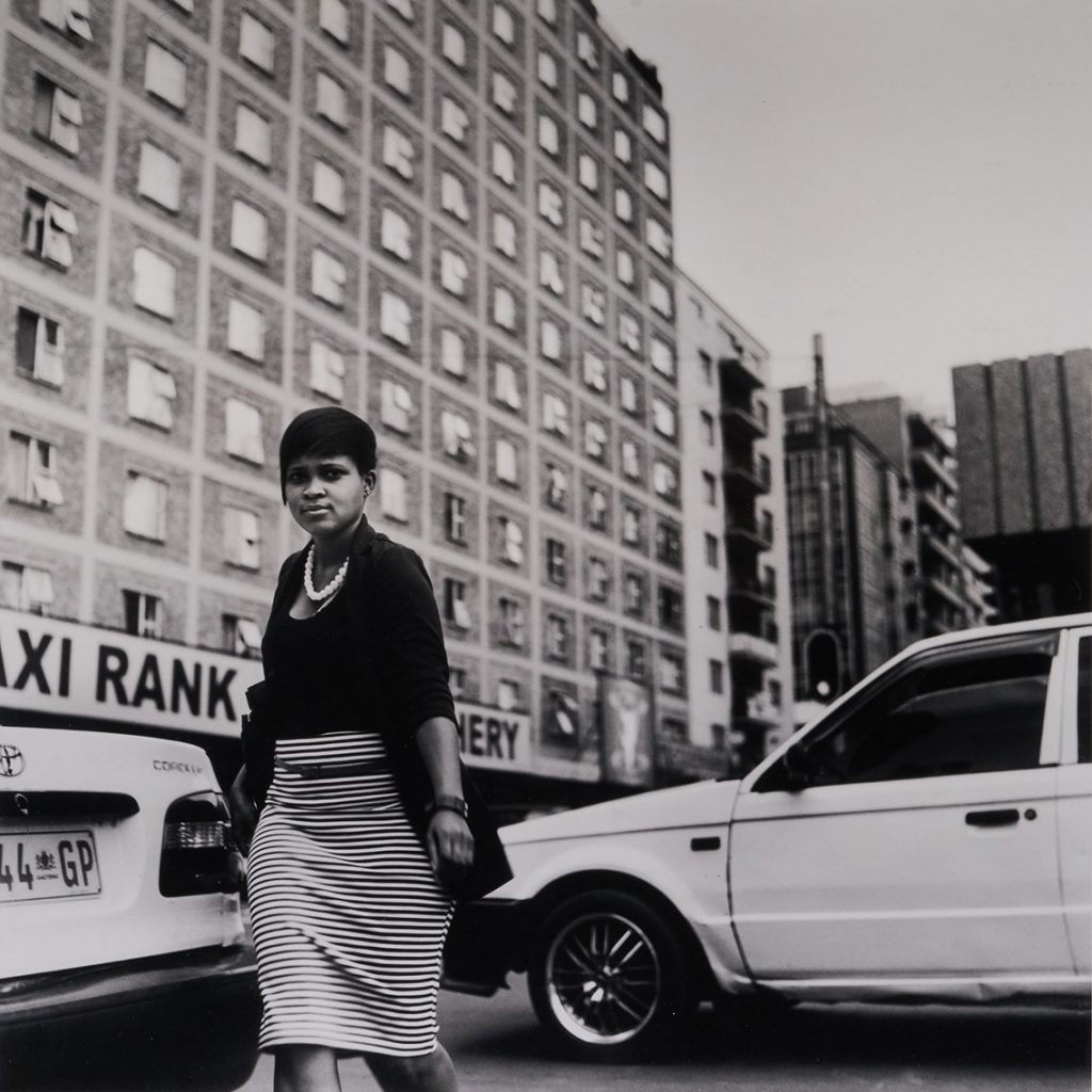 black and white photo of a person next to several cars
