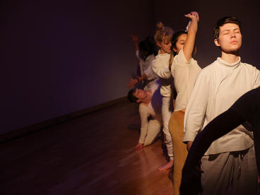 dancers moving in a line on a wooden studio floor