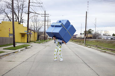 A person carrying massive blue luggage on his back