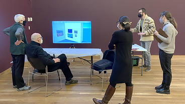 Five people around a table discussing the exhibition design of B.J.O. Nordfeldt: American Internationalist exhibition