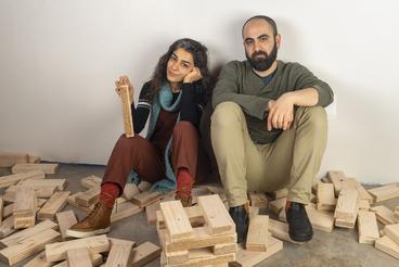 2 people sitting on a floor with wooden blocks