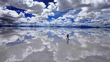 A person walking underneath a cloudy sky