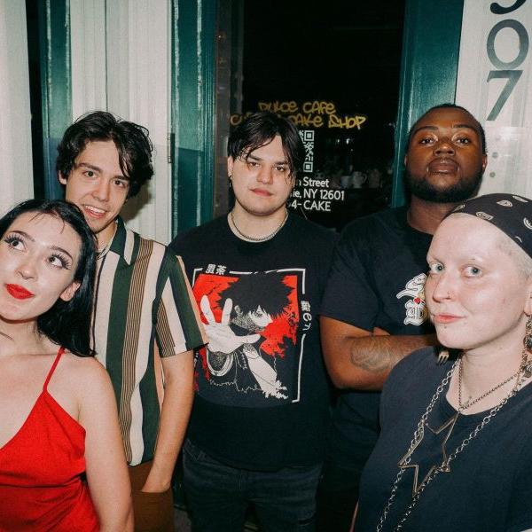 A group of female presenting musicians stand together for a sassy band photo